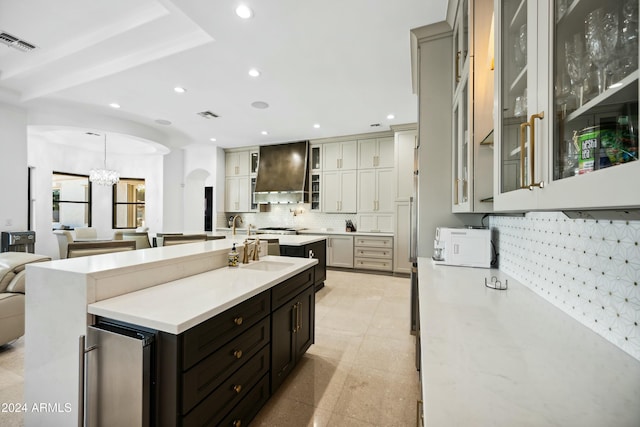 kitchen with decorative backsplash, custom exhaust hood, an inviting chandelier, wine cooler, and hanging light fixtures