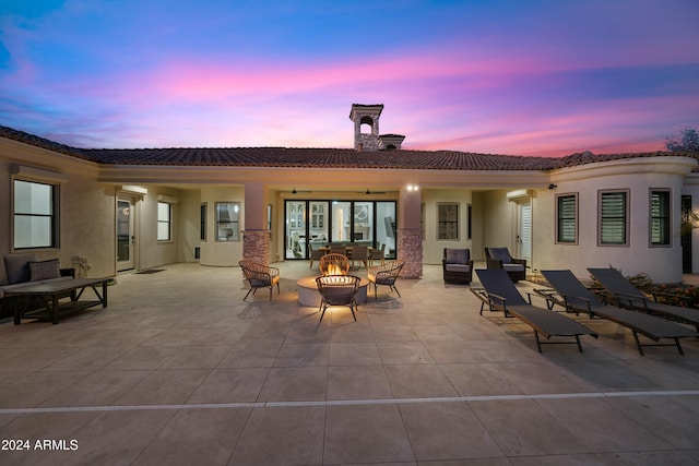 back house at dusk featuring an outdoor fire pit and a patio