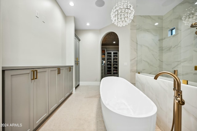 bathroom with a tub to relax in and an inviting chandelier