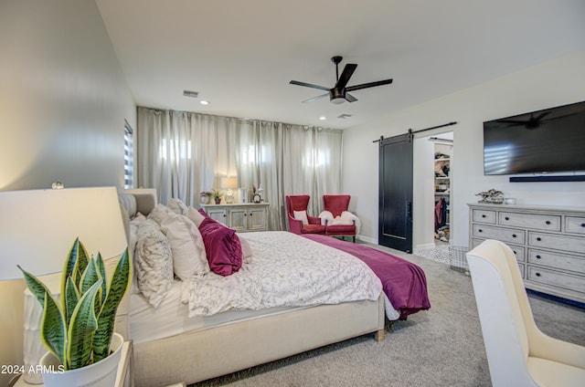 bedroom featuring carpet flooring, ceiling fan, a barn door, a walk in closet, and a closet