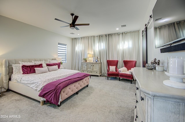 carpeted bedroom featuring a barn door and ceiling fan