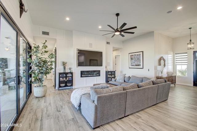 living room with light hardwood / wood-style flooring and ceiling fan with notable chandelier