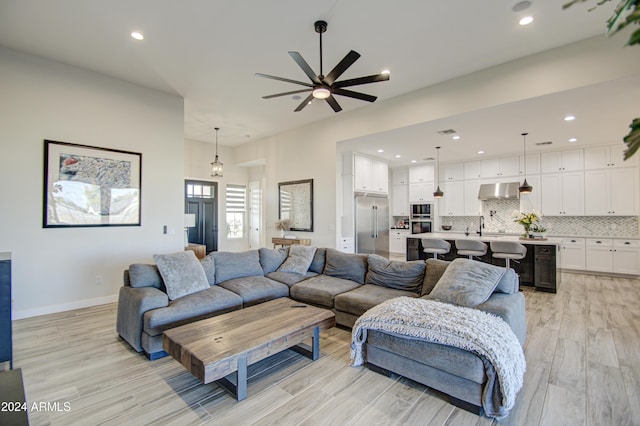 living room with light hardwood / wood-style flooring, ceiling fan, and sink