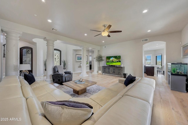 living area featuring arched walkways, decorative columns, light wood finished floors, recessed lighting, and visible vents