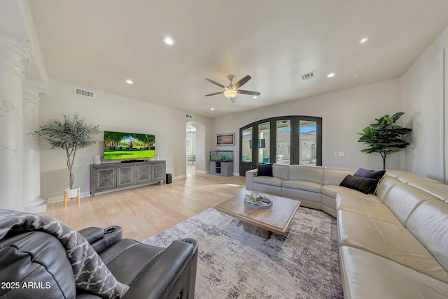 living area with light wood finished floors, visible vents, arched walkways, and recessed lighting