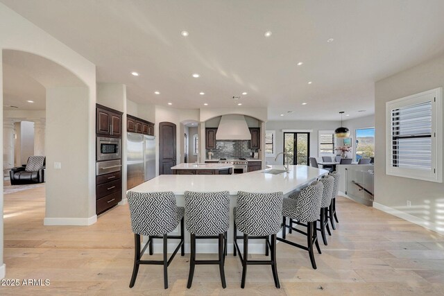 kitchen with built in appliances, light countertops, a breakfast bar, and a spacious island