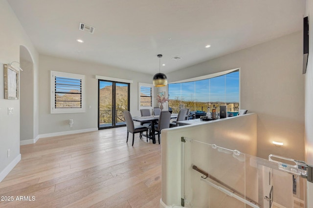 dining space with arched walkways, recessed lighting, visible vents, light wood-type flooring, and baseboards