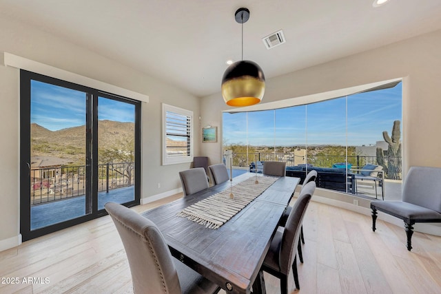 dining area featuring light wood-style floors, baseboards, and visible vents