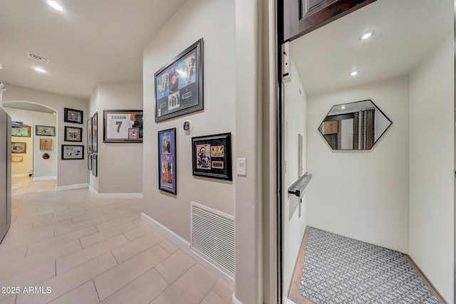 corridor featuring arched walkways, visible vents, baseboards, and recessed lighting