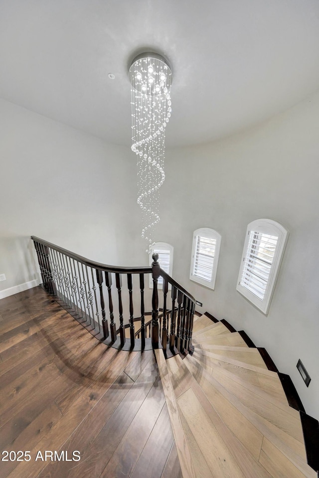 stairs featuring a notable chandelier and wood finished floors