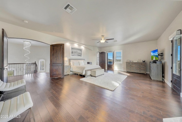 bedroom with baseboards, visible vents, arched walkways, dark wood-style floors, and ceiling fan