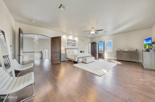 bedroom featuring baseboards, visible vents, arched walkways, and wood finished floors