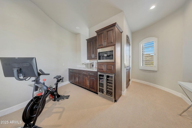 workout area featuring recessed lighting, beverage cooler, light colored carpet, and baseboards