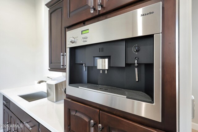 kitchen featuring dark brown cabinetry, light countertops, a sink, and oven