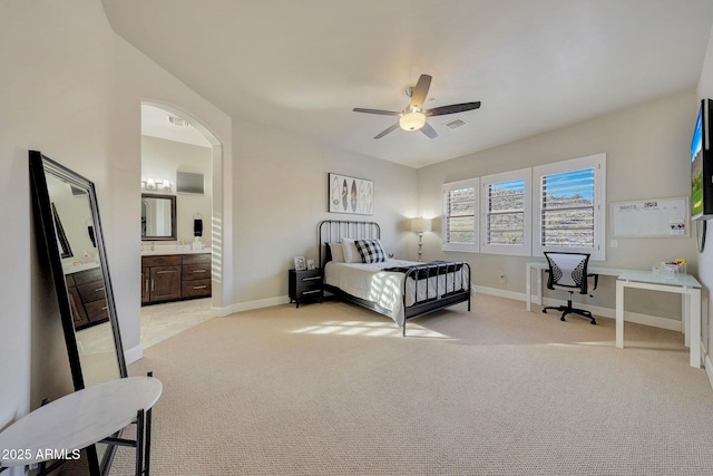 bedroom with arched walkways, light colored carpet, visible vents, and baseboards