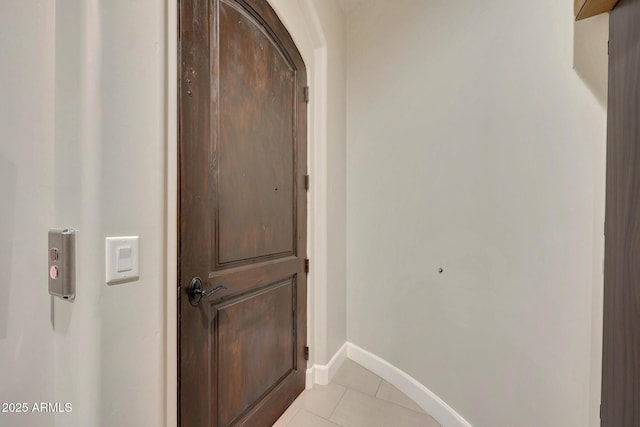 hallway with light tile patterned floors and baseboards