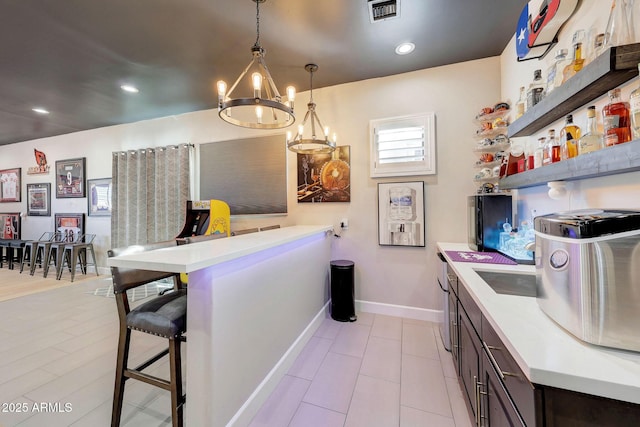 kitchen featuring hanging light fixtures, visible vents, light countertops, and dark brown cabinets