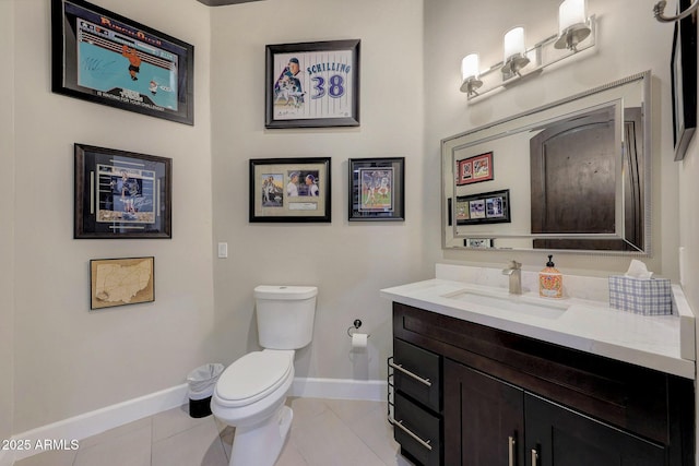 half bathroom with baseboards, vanity, toilet, and tile patterned floors