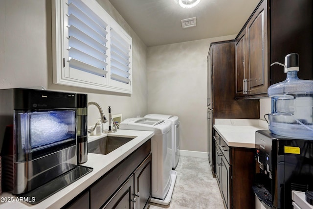 clothes washing area featuring laundry area, visible vents, baseboards, washing machine and dryer, and a sink