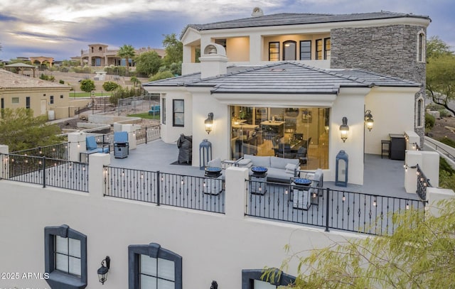 back of property at dusk with outdoor lounge area and stucco siding