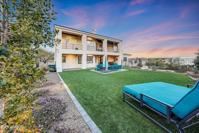 back of house with a lawn, a balcony, a fenced backyard, an outdoor living space, and stucco siding