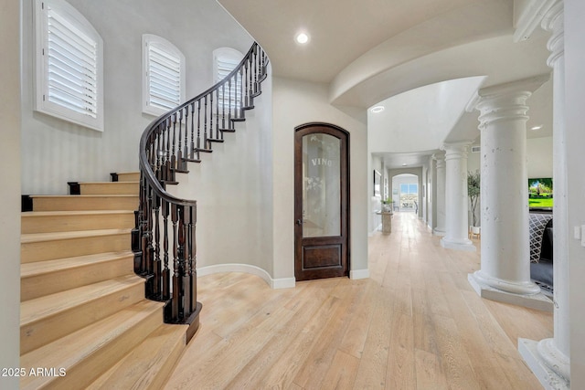 entrance foyer with recessed lighting, ornate columns, wood finished floors, baseboards, and stairs