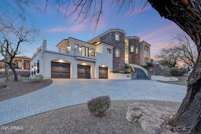 view of front of house with a balcony, stone siding, decorative driveway, and stucco siding