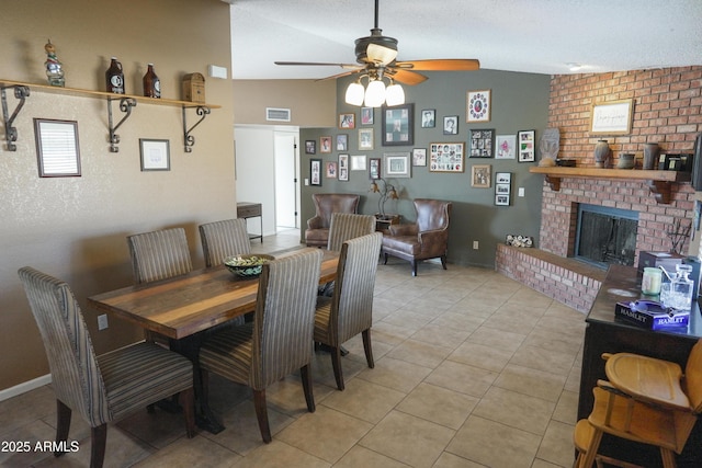 dining space featuring lofted ceiling, light tile patterned floors, ceiling fan, a fireplace, and a textured ceiling