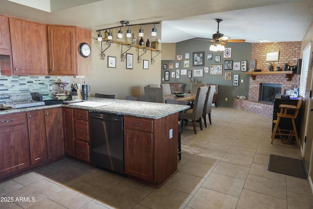 kitchen with vaulted ceiling, a brick fireplace, light tile patterned floors, and kitchen peninsula