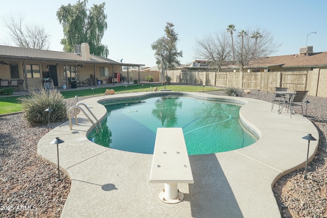 view of pool with central AC, a diving board, and a patio