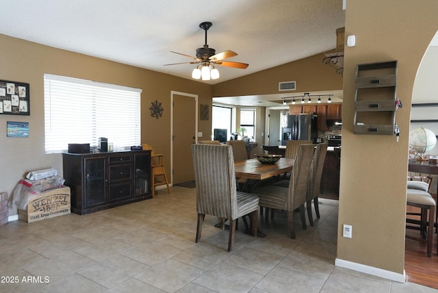 dining space with light tile patterned flooring, ceiling fan, vaulted ceiling, and a textured ceiling