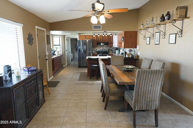 tiled dining area featuring ceiling fan and vaulted ceiling