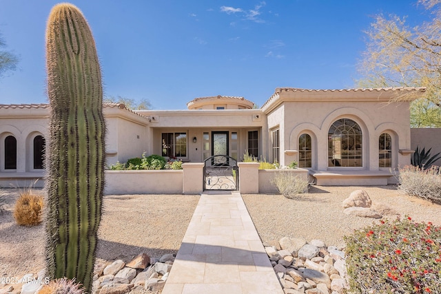 mediterranean / spanish home with a gate and stucco siding