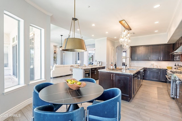 kitchen with arched walkways, high end range, a kitchen island with sink, dark brown cabinets, and a sink