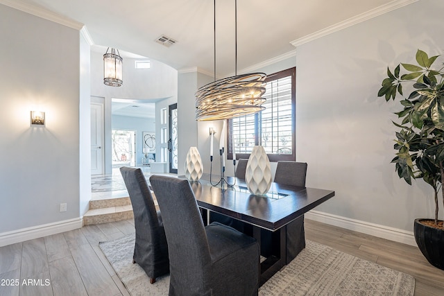 dining room featuring light wood-style floors, baseboards, visible vents, and ornamental molding