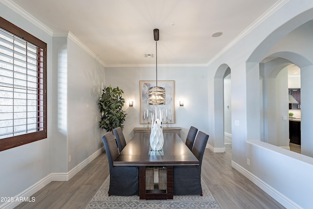 dining area featuring crown molding, baseboards, and wood finished floors