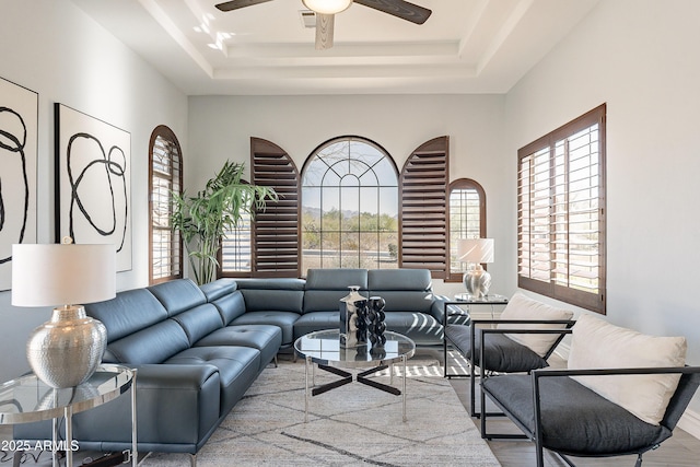 living room with a raised ceiling, visible vents, ceiling fan, and wood finished floors