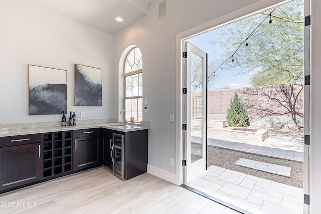 bar featuring recessed lighting, a sink, light wood-type flooring, beverage cooler, and baseboards