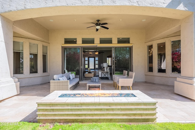 view of patio featuring a ceiling fan and an outdoor living space with a fire pit