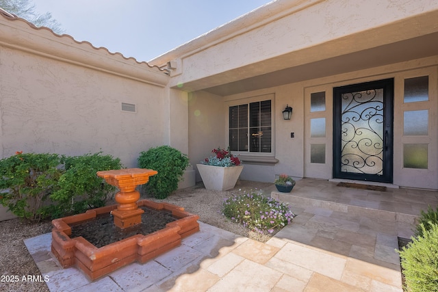 property entrance with a tile roof and stucco siding