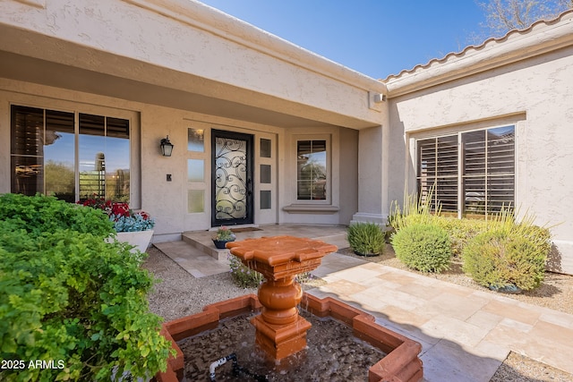 entrance to property featuring covered porch, a tiled roof, and stucco siding