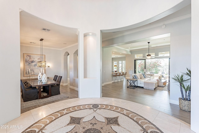 interior space featuring arched walkways, visible vents, crown molding, and baseboards