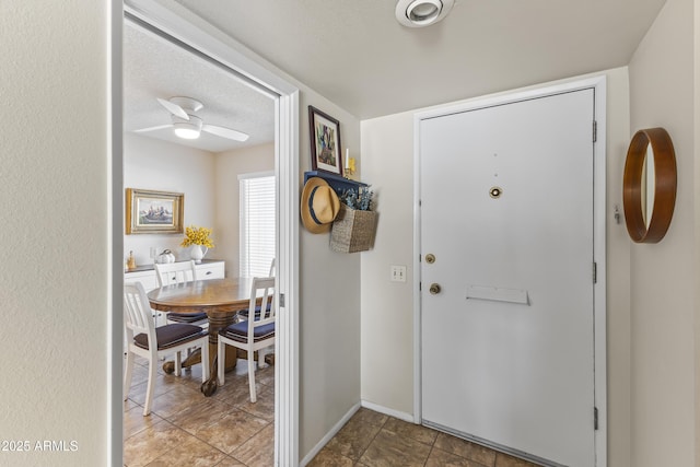 tiled entrance foyer featuring a textured ceiling and ceiling fan