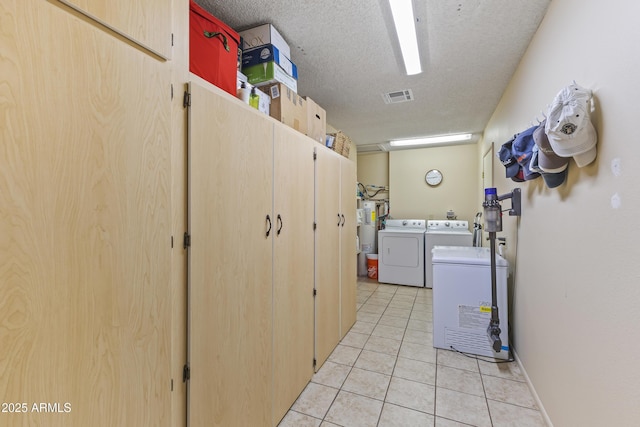 laundry room with independent washer and dryer, electric water heater, a textured ceiling, and light tile patterned floors