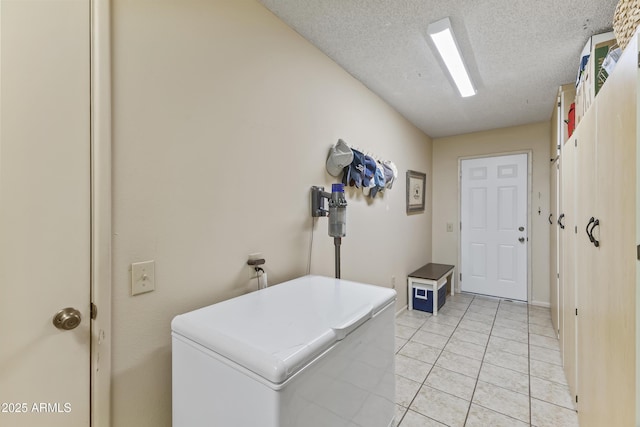 interior space featuring light tile patterned floors, washer and dryer, and a textured ceiling