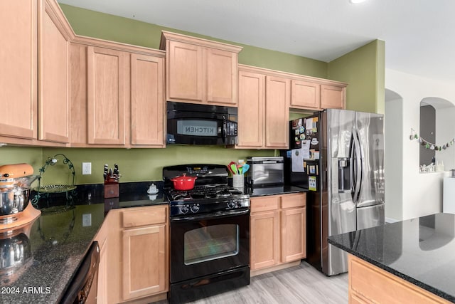 kitchen featuring dark stone countertops, light brown cabinets, black appliances, and light hardwood / wood-style floors