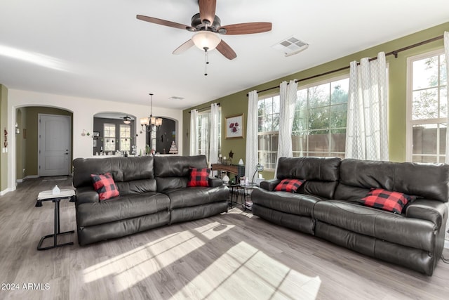 living room featuring ceiling fan with notable chandelier and light wood-type flooring