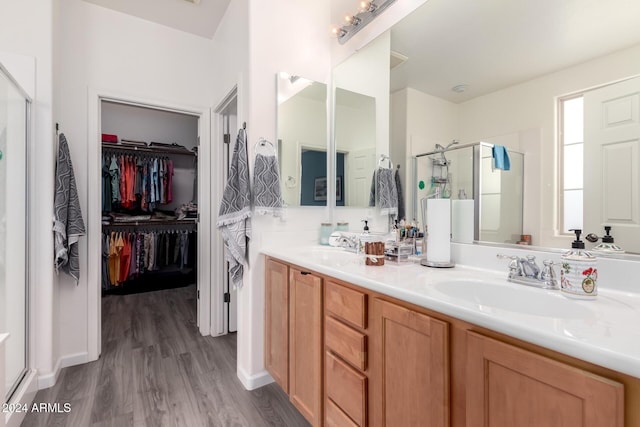 bathroom with hardwood / wood-style floors, vanity, and a shower with door