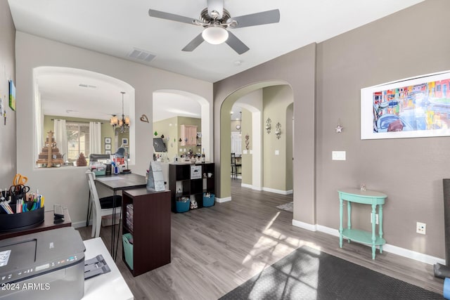 office area featuring ceiling fan with notable chandelier and wood-type flooring