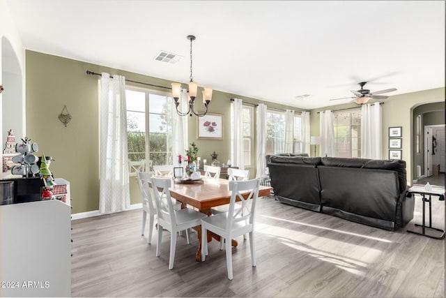 dining area with ceiling fan with notable chandelier and light hardwood / wood-style flooring